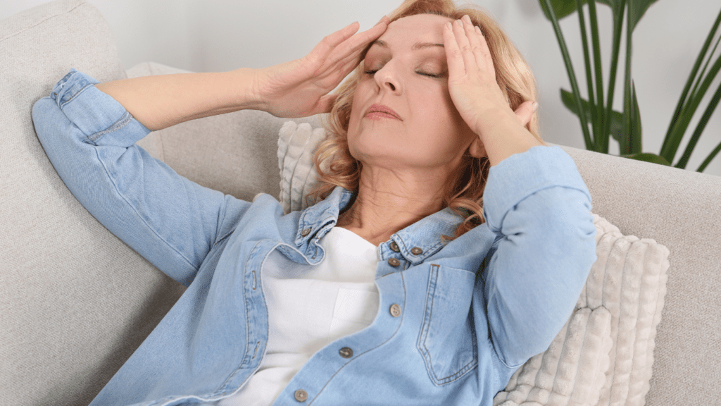 a woman sitting on a couch with her hands on her head