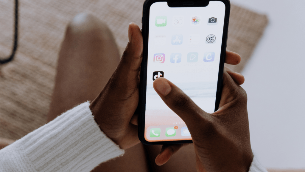 a person holding an iPhone while sitting on a couch