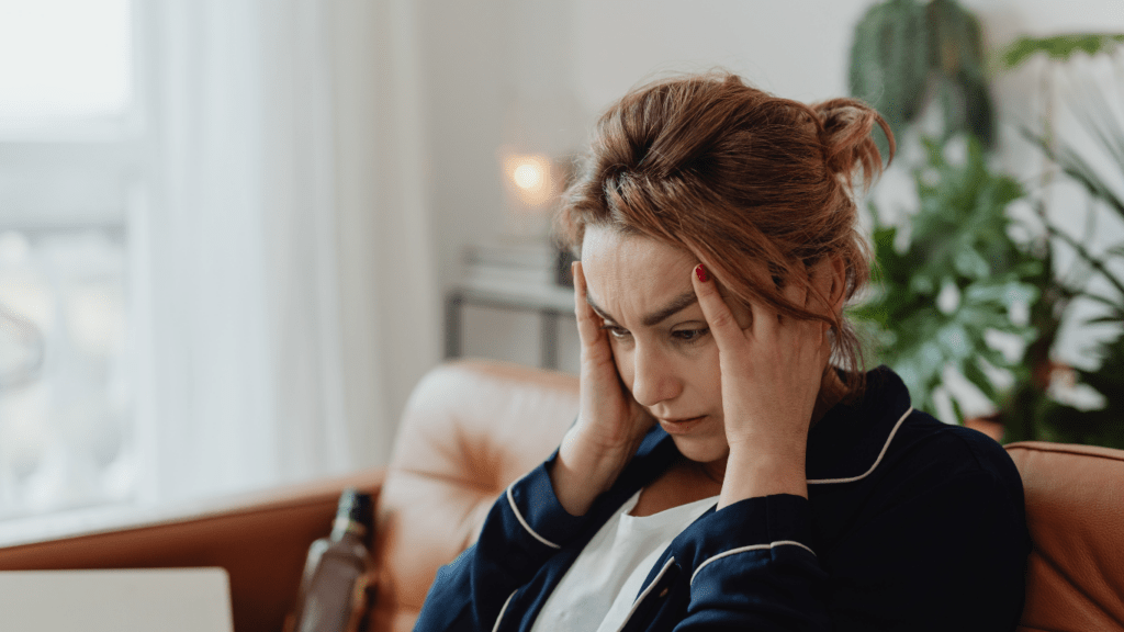 a person covers their face with their hands while sitting on a couch