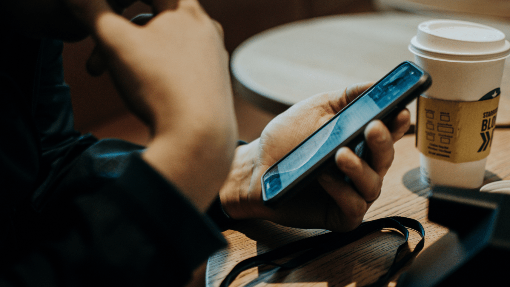 a person holding a cell phone while sitting at a table