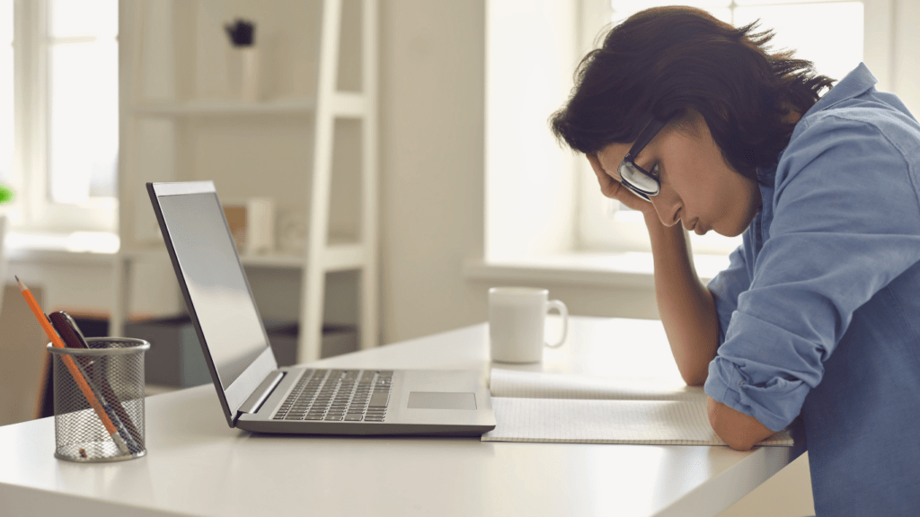 a person is sitting at a desk with their head in their hands