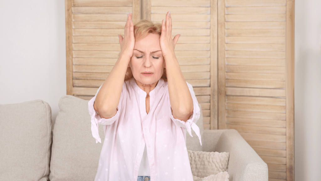 a woman sitting on a couch with her hands on her head